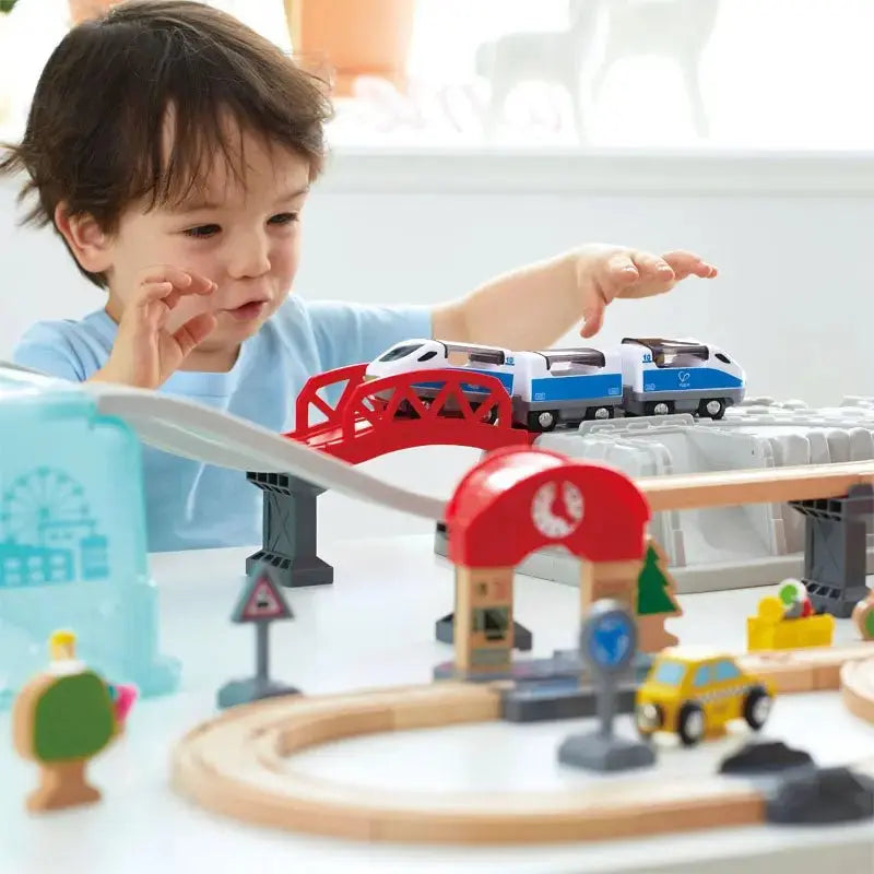 Child playing with a toy train set on a table